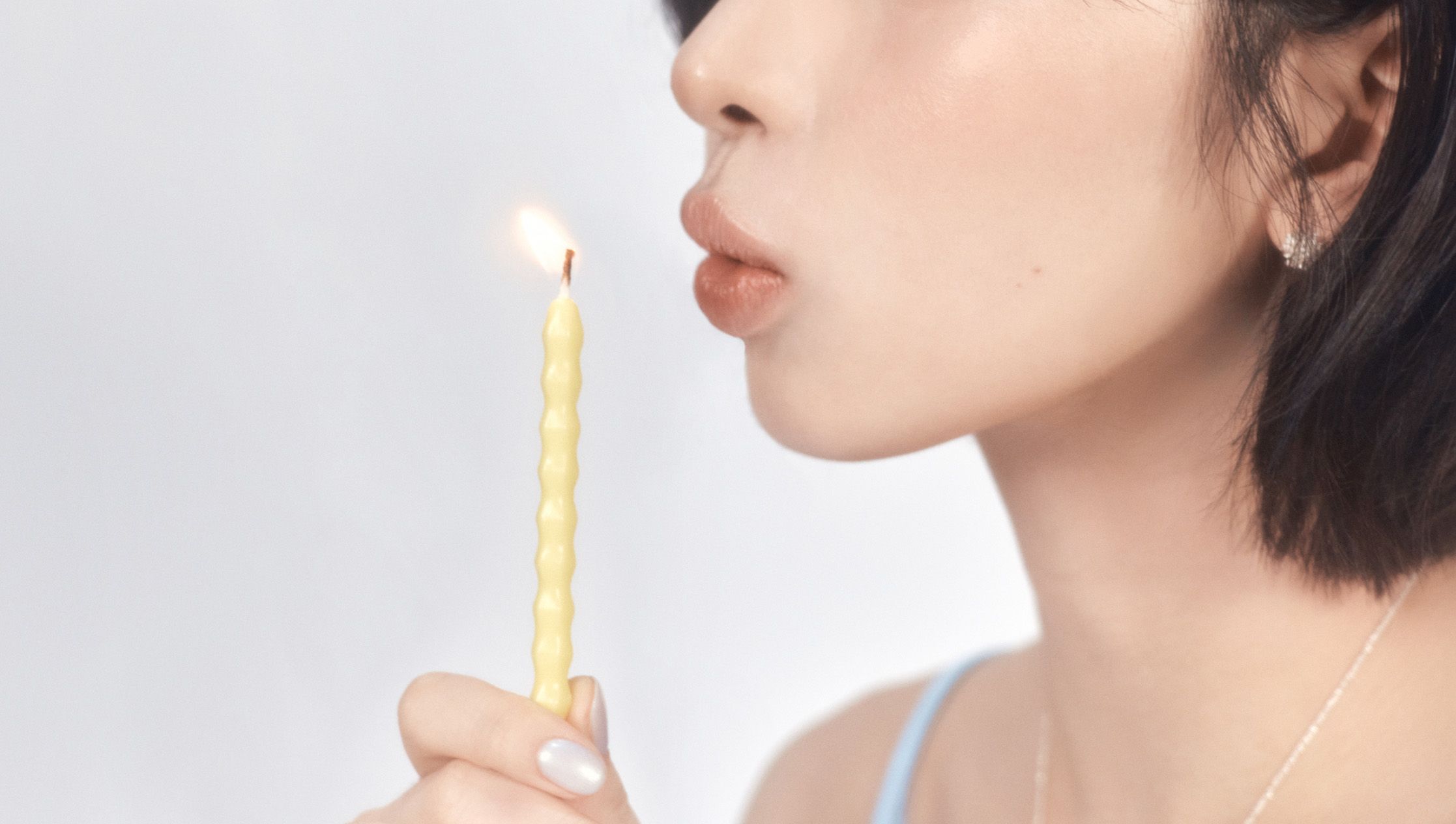 Leaning in to blow out a single lit candle